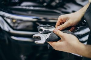 Des mains et des clés de garagiste avec un moteur de voiture en arrière-plan pour l'entretien