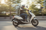 Jeune homme sur un scooter gris en train de rouler